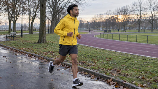 Runner jogging beside a park track at dawn